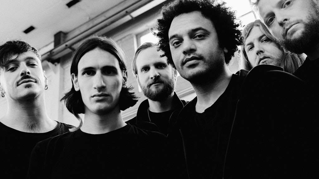 Black and white shot of the six members of Zeal & Ardor gazing into the camera with relative seriousness.