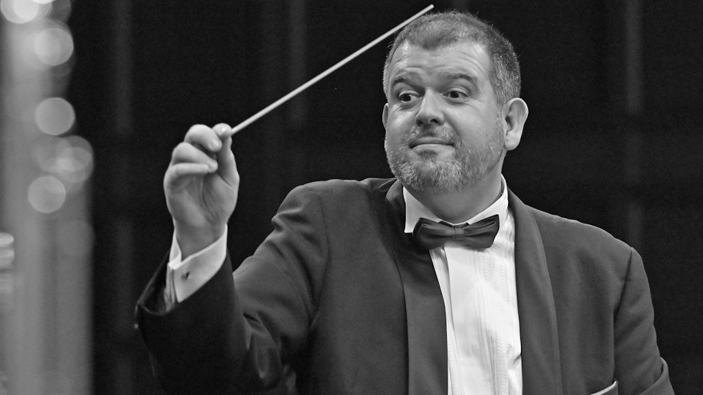 Carlo Balmelli dirige avec la baguette de chef d'orchestre levée.