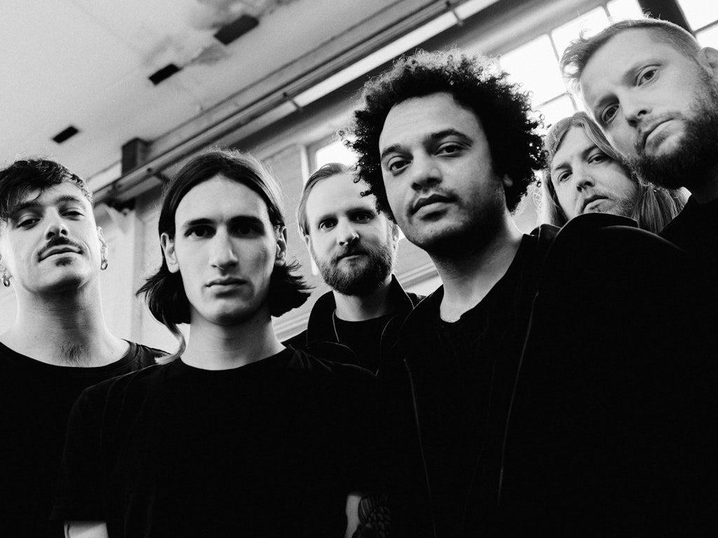 Black and white shot of the six members of Zeal & Ardor gazing into the camera with relative seriousness.
