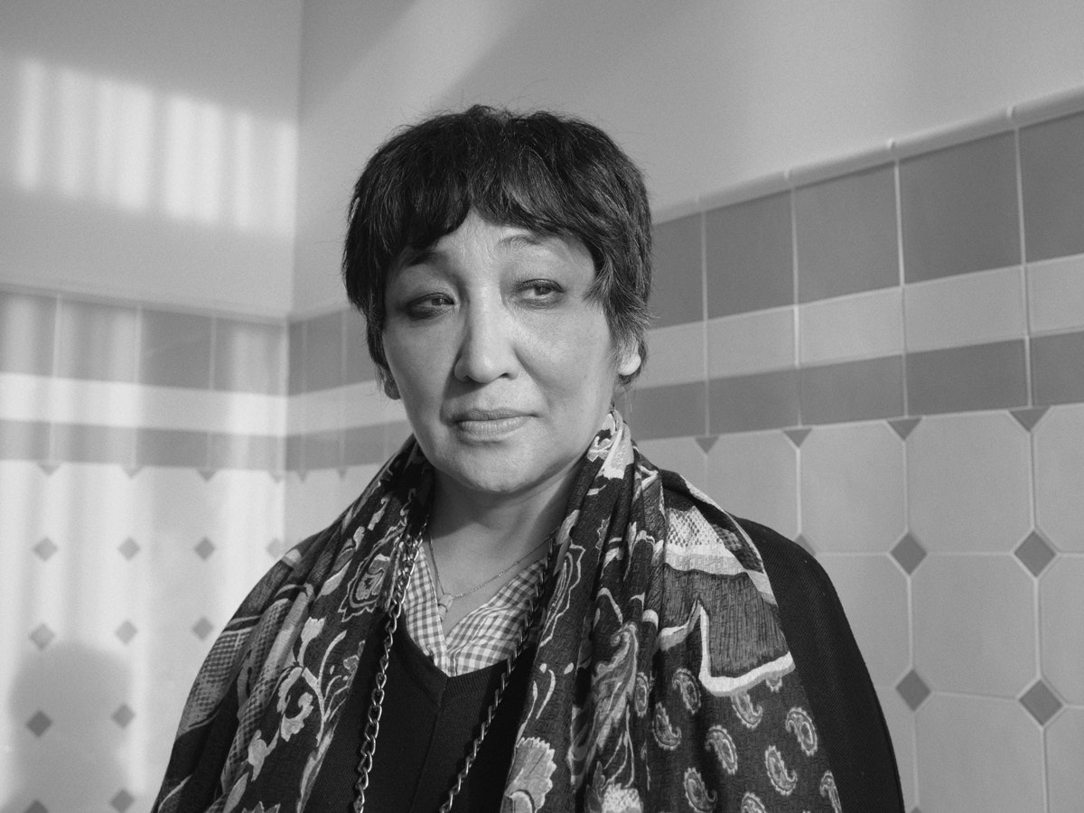 Portrait de Saadet Türköz. Elle se tient devant un mur décoré de carreaux de faïence.