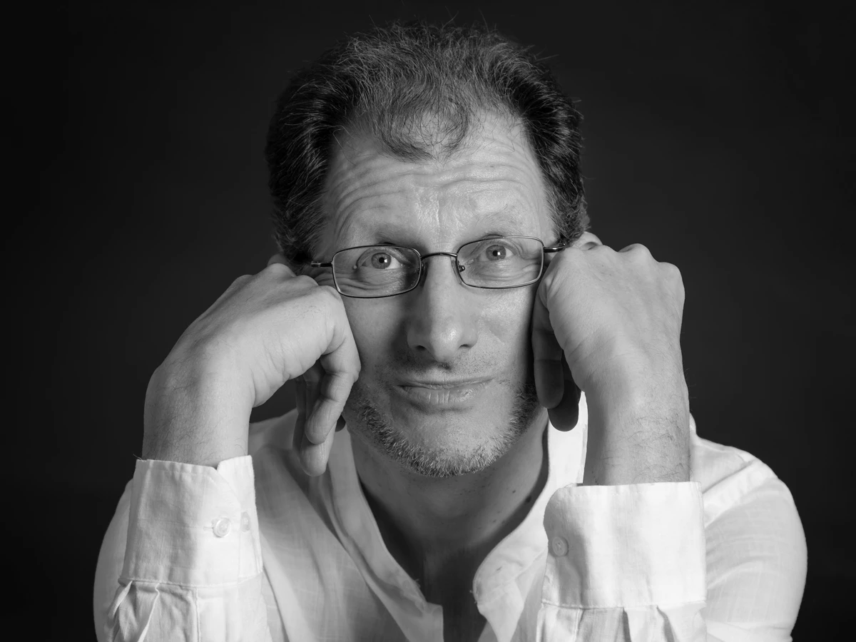 Foto in bianco e nero di Ivo Antognini. Tiene la testa tra le mani e guarda verso l'bbiettivo.