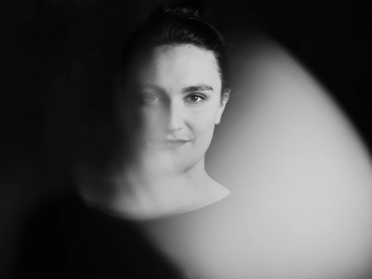 Foto in bianco e nero di Simone Felber. Guarda direttamente nella fotocamera con un leggero sorriso sul volto.